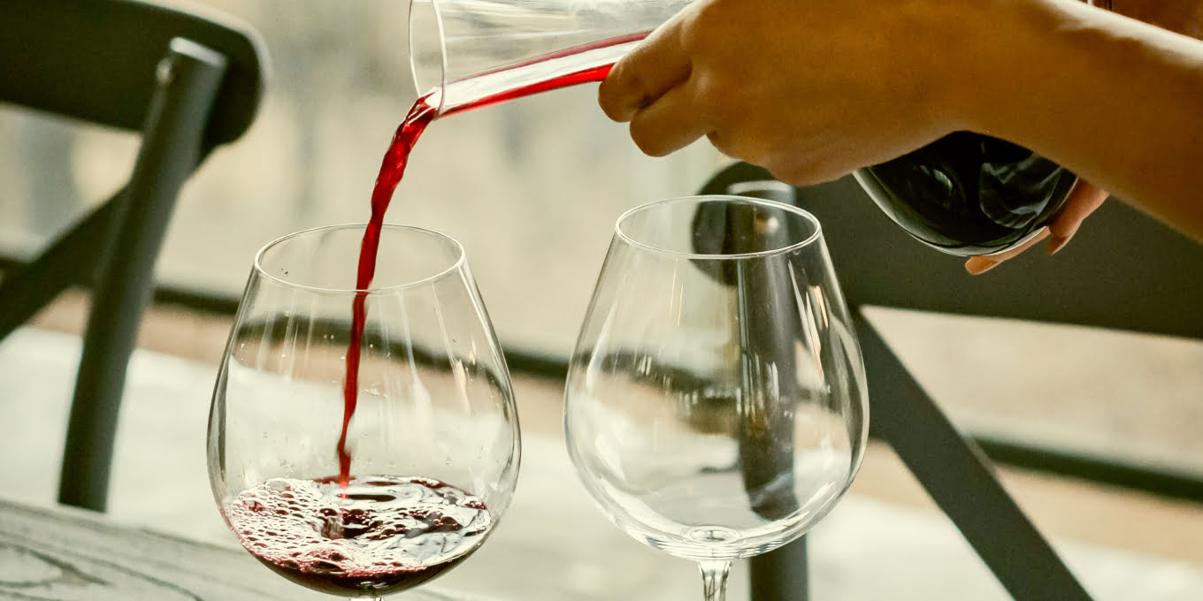 A woman pouring some wine from a Decanter. The Tannat wine is known for its color so the use of a decanter is a great way to make prettier color more highlighted and also enhance the flavor.
