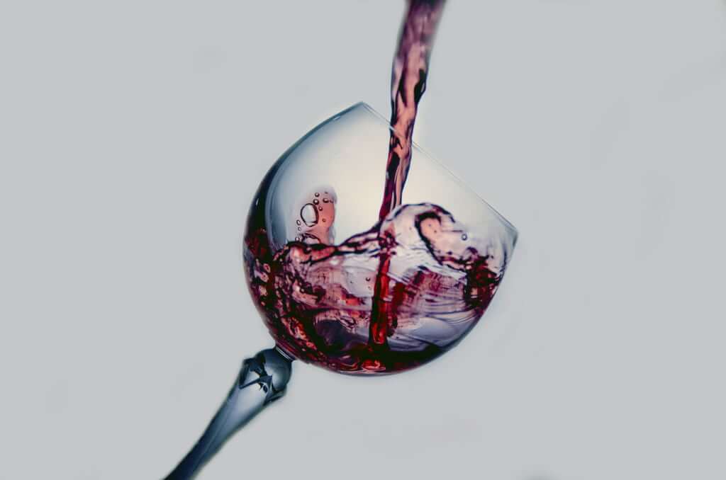 pouring wine on a glass. Color is one aspect on how to choose a red wine